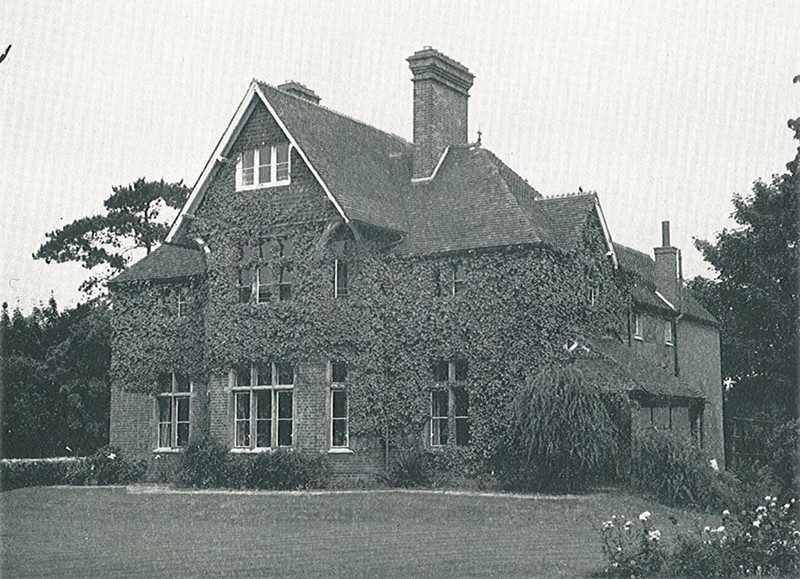 Photo of the Vicarage showing most of its south-facing walls covered with ivy