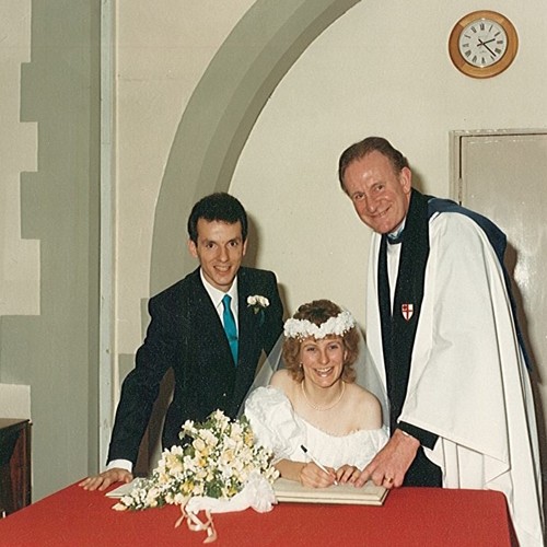 Wedding photo of Stephen and Ruth Thorp, Ruth is signing the register as a smiling John Short points to the place to sign