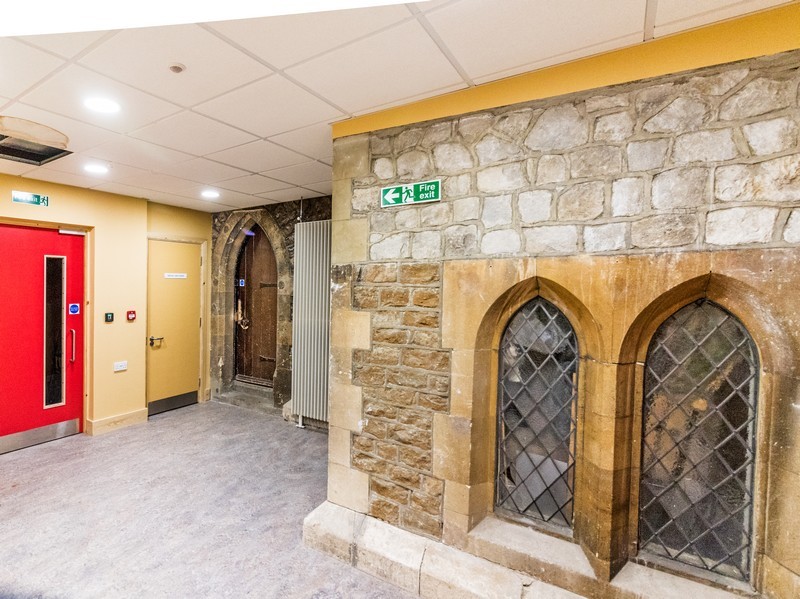 Photo of the interior of the New Halls as you enter from the lounge, the main feature of interest being the old north wall and windows visible on the right, with the door to the vestry further along