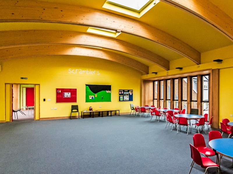 Photo of the new Scrambler's room looking towards the Climber's Room, with small blue tables and small red chairs on the right, yellow painted walls and 'Scramblers' painted on the far wallyellow painted walls