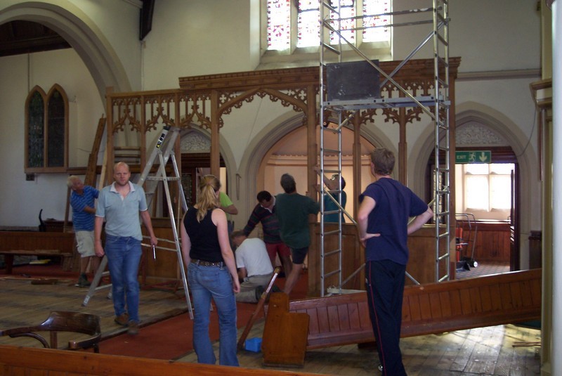 Photo showing the re-ordering at an early stage, looking towards the west wall. In view are a number of CCNM volunteers, working on removal of the oak screen, with pews already removed