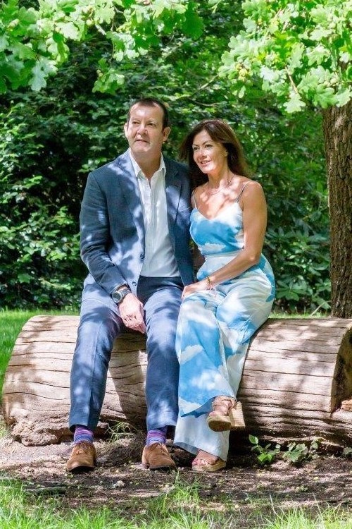 John and Georgie Morris sat together in a wood, on a huge section of tree