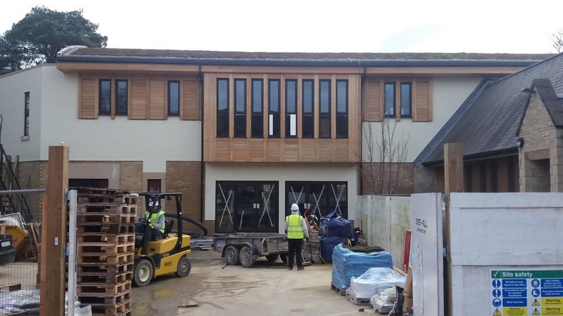 Photo of the New Hall now virtually complete whilst the car park is still obviously part of a building site, a stack of palletes visible in the foreground to the left