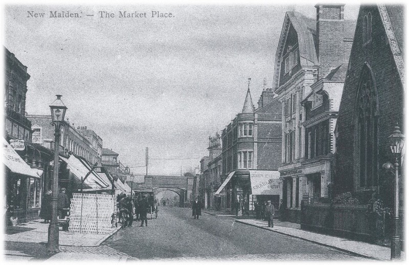 Postcard showing New Malden High Street and Market Place, the railway bridge visible in the distance