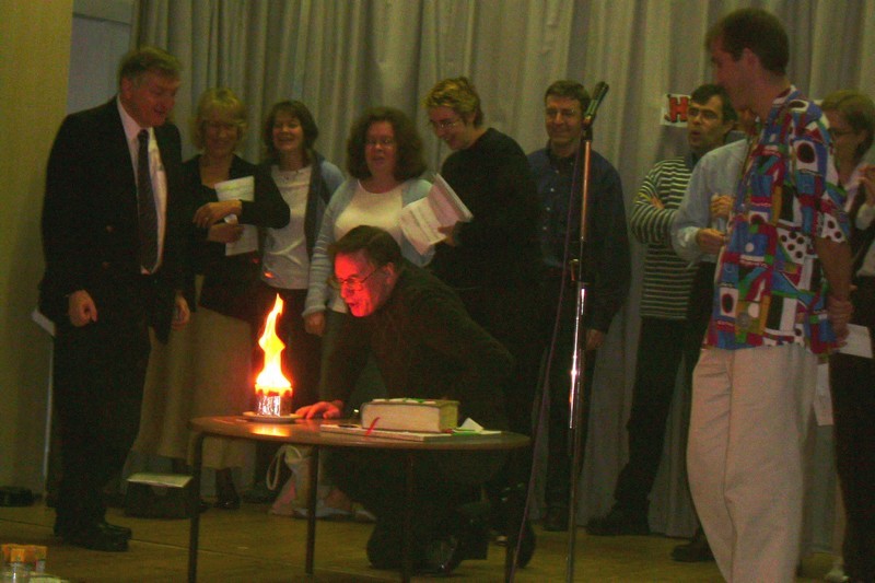 Stewart Downey blowing out the candles at his 65th Birthday Party in the Parish Halls. Visible in the background are Trevor Webster, Barbara Griffiths, Sarah Parker, Ruth Henson, Patrick Gardner and Jon Cook